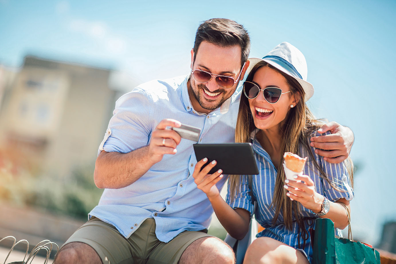 Happy,Couple,Paying,On,Line,With,Credit,Card,And,Digital man and woman smiling at tablet with debit card in hand
