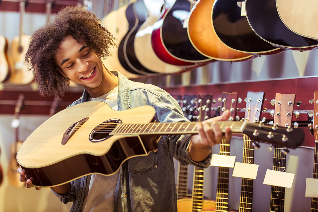 Handsome,Young,Afro-american,Man,Holding,A,Guitar,,Examining,It,And man looking at guitar