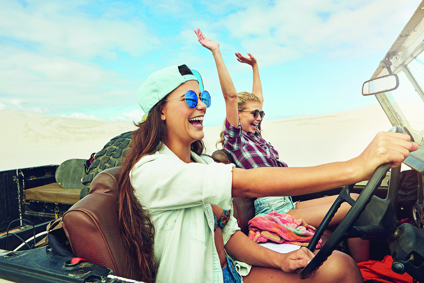 Going on an epic desert adventure two young women smiling while driving jeep